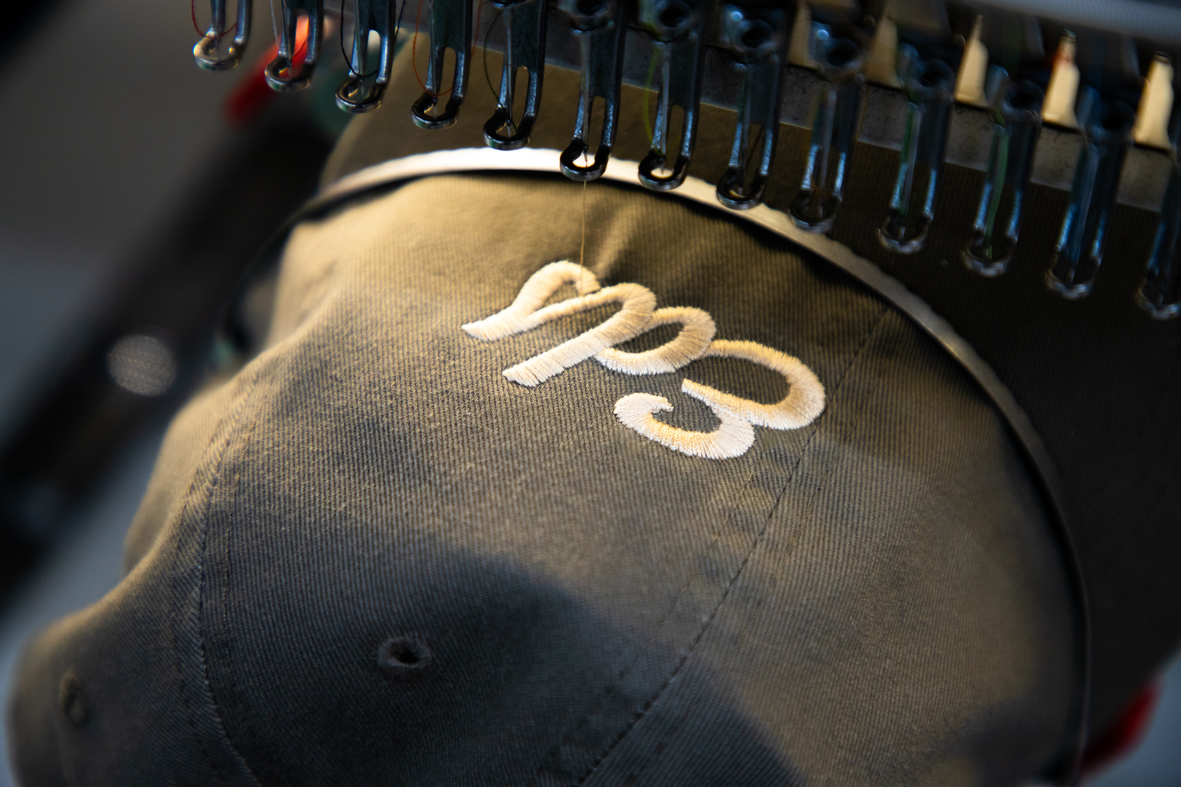 Custom embroidered hat being stitched on commercial embroidery machine in production