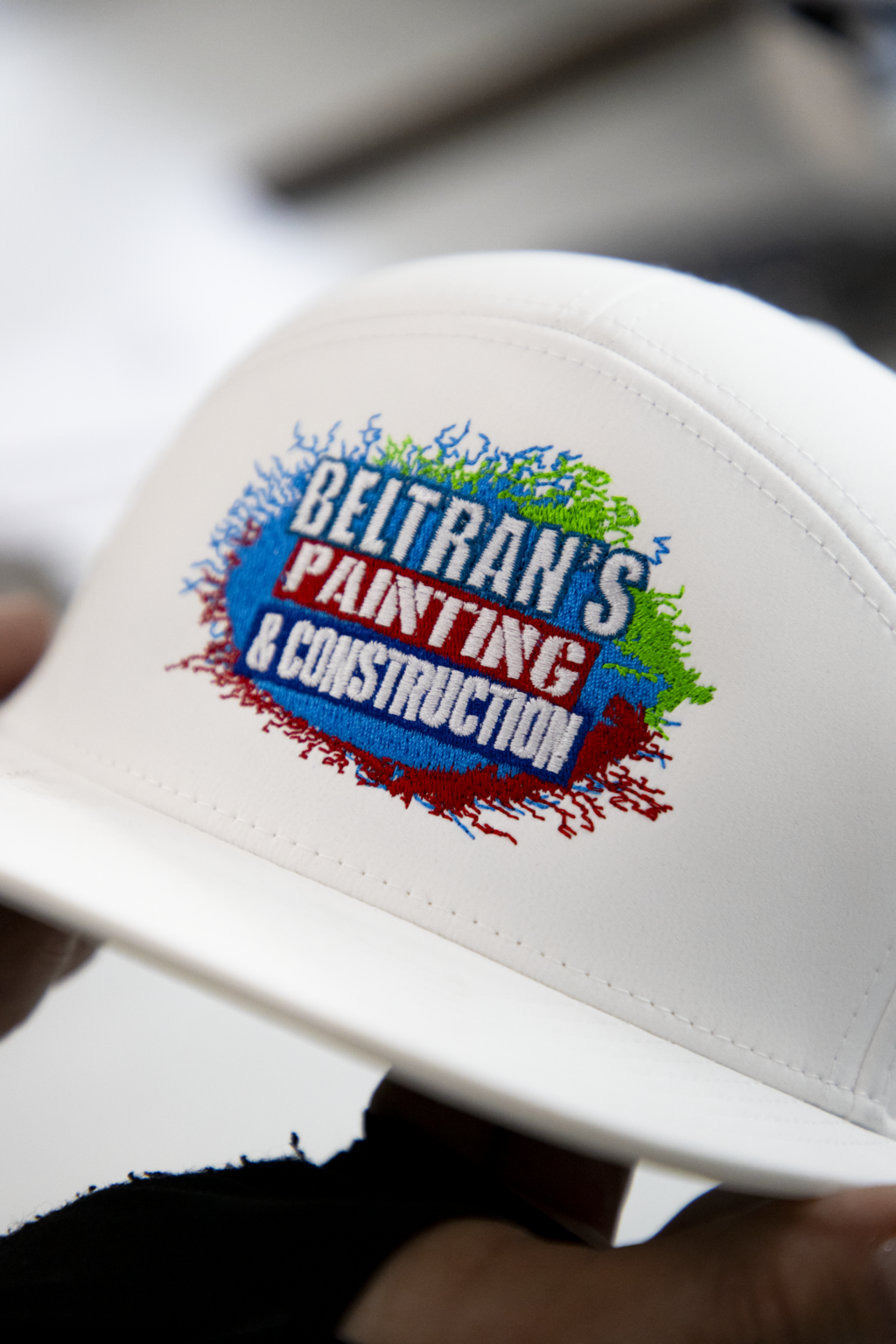 Custom embroidered logo for Beltrans Painting & Construction on white cap