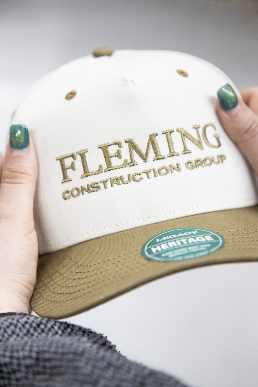 Custom embroidered logo for Fleming Construction Group on white and beige trucker cap