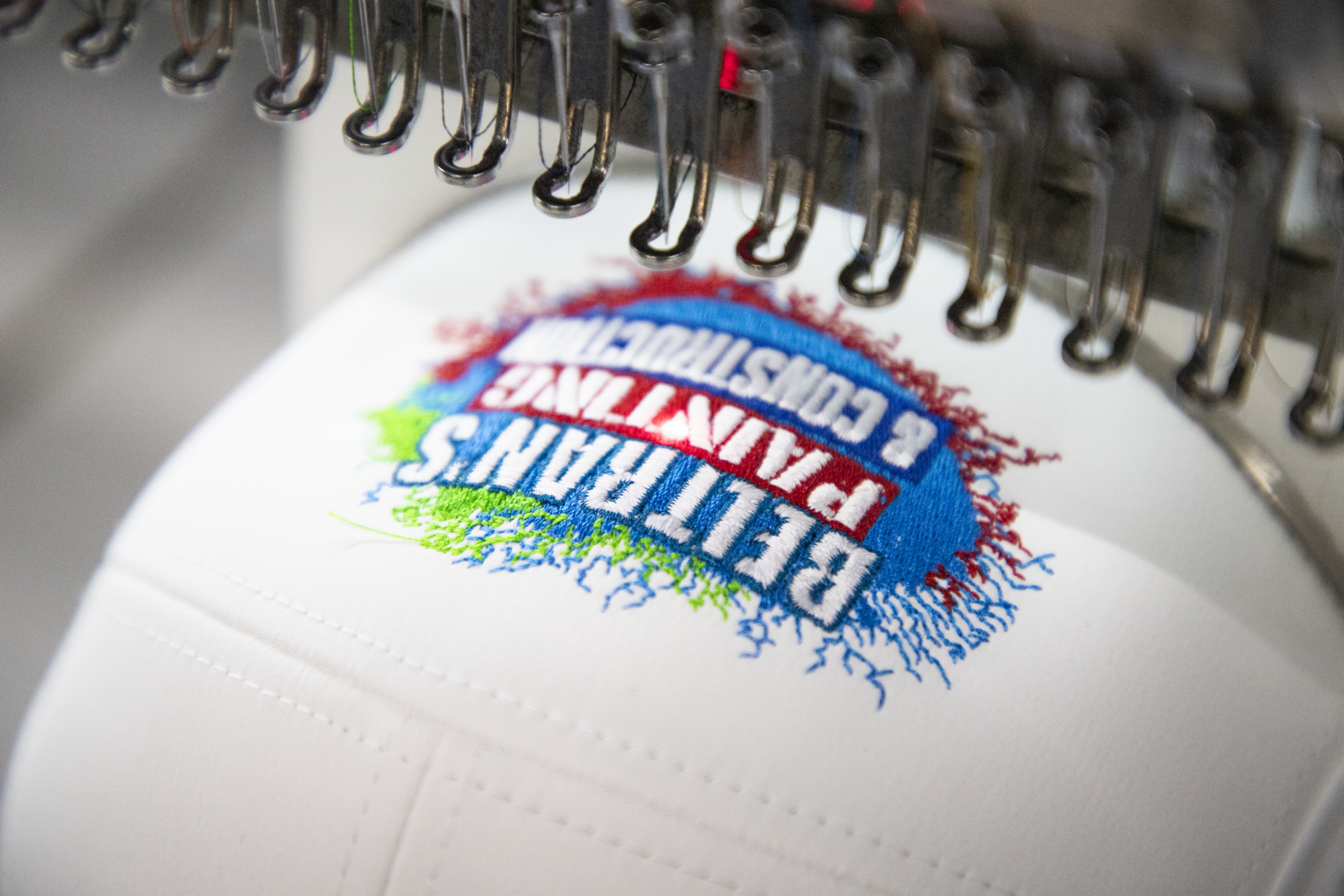 Close-up of multicolor custom embroidery on hat showing detailed stitching during production