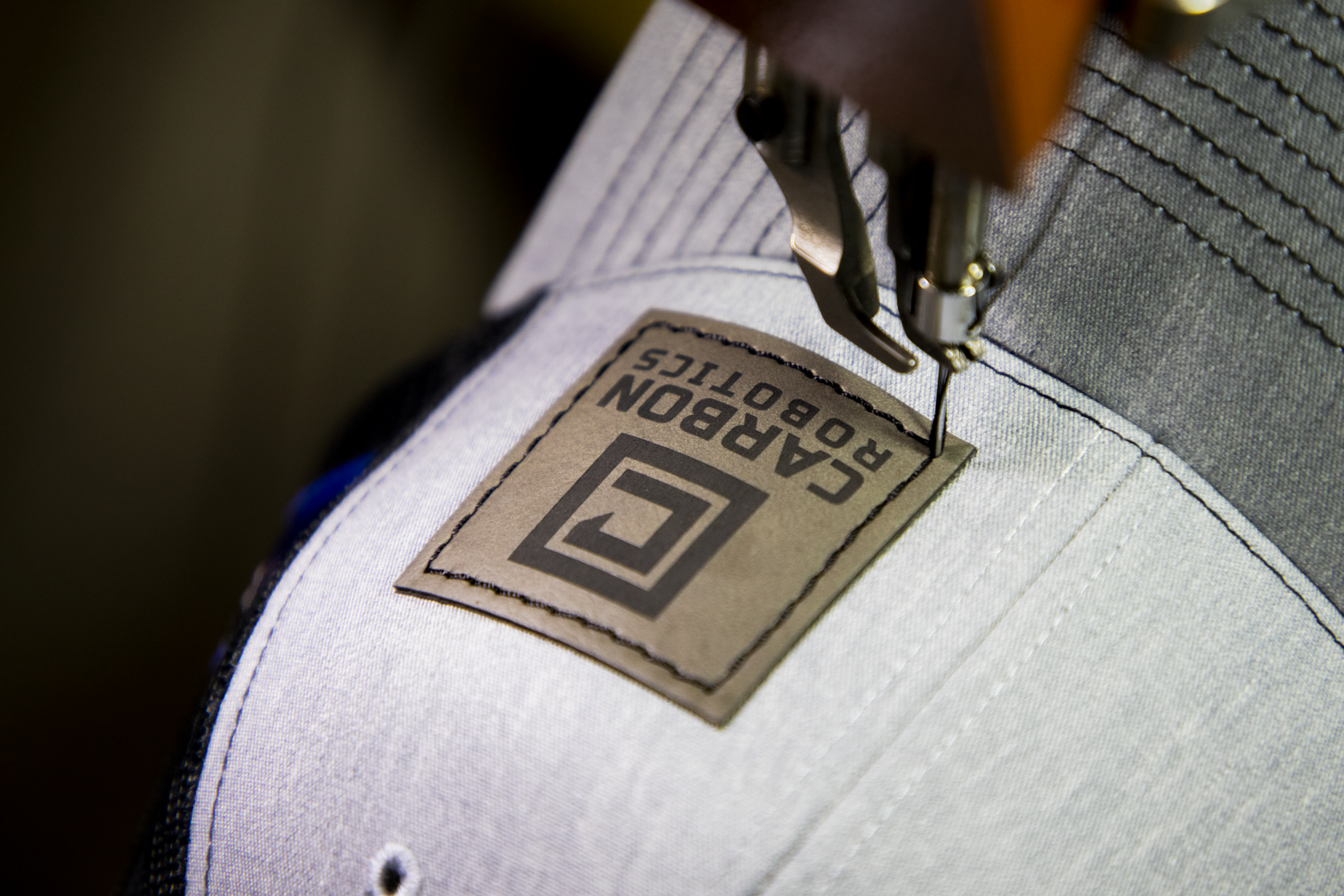 Custom leather patch being sewn onto hat using industrial sewing machine for durable application