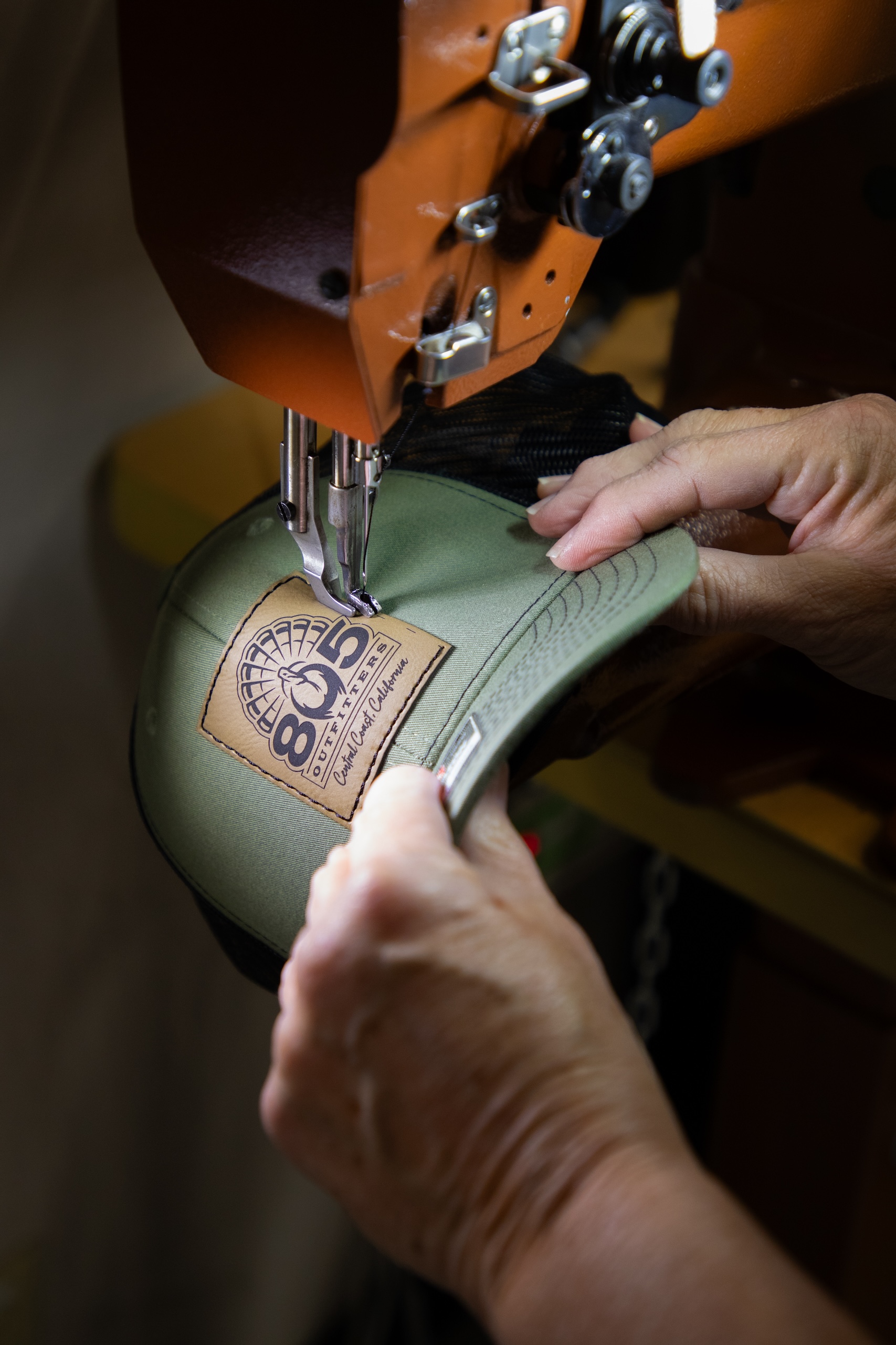 Leather patch being sewn onto custom hat during in-house production process